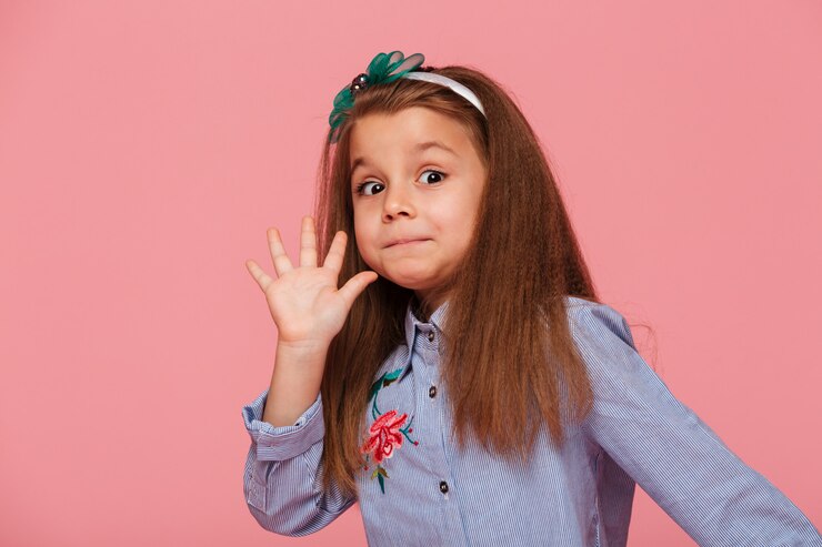 Foto grátis retrato de criança do sexo feminino engraçado com cabelo ruivo longo olhando dando alto significado cinco oi ou tchau com a mão
