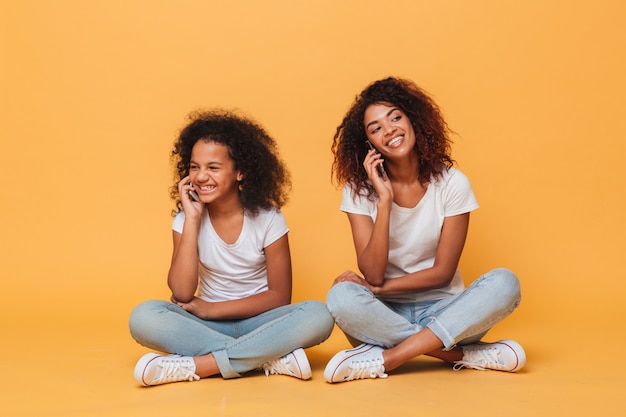 Retrato de duas irmãs afro-americanas alegres falando por pohone