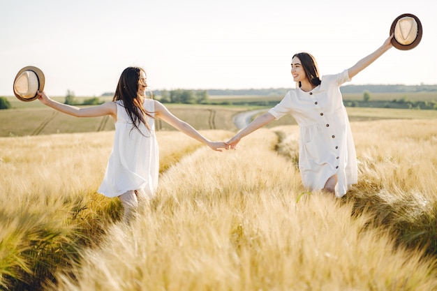 Retrato de duas irmãs em vestidos brancos com cabelos longos em um campo