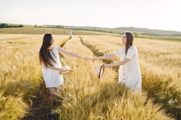Retrato de duas irmãs em vestidos brancos com cabelos longos em um campo