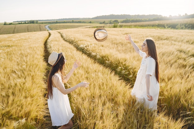 Retrato de duas irmãs em vestidos brancos com cabelos longos em um campo