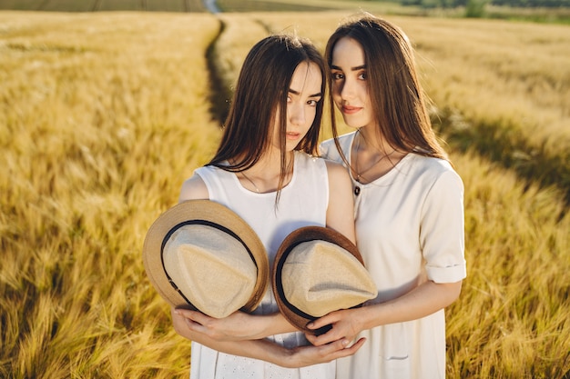 Foto grátis retrato de duas irmãs em vestidos brancos com cabelos longos em um campo