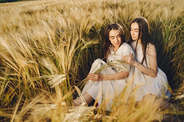 Retrato de duas irmãs em vestidos brancos com cabelos longos em um campo