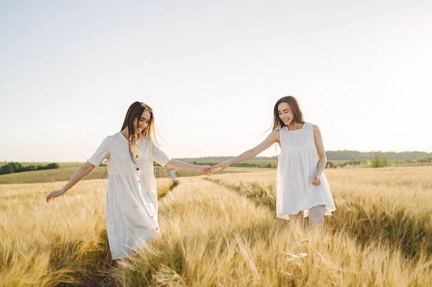 Retrato de duas irmãs em vestidos brancos com cabelos longos em um campo