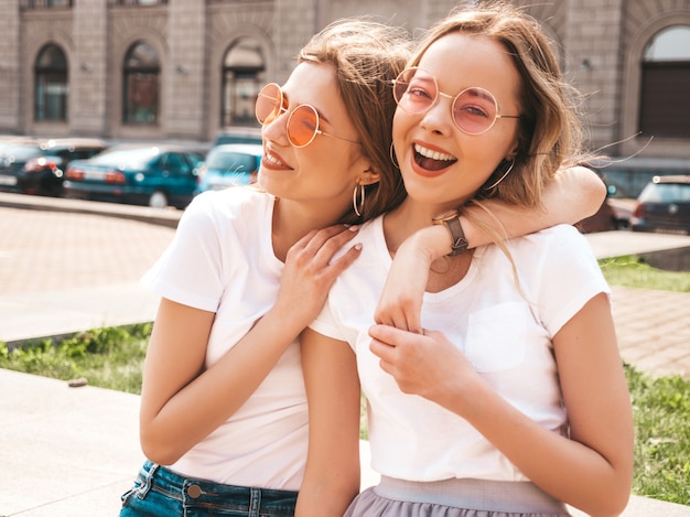 Retrato de duas meninas de hipster loira sorridente jovem bonita em roupas de camiseta branca na moda verão.