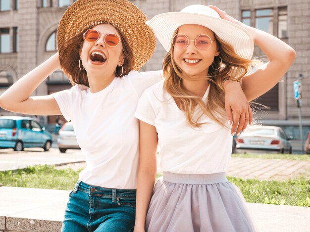 Retrato de duas meninas de hipster loira sorridente jovem bonita em roupas de camiseta branca na moda verão.