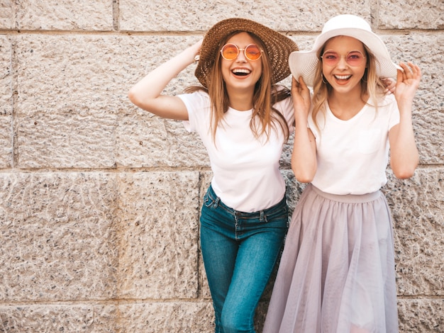 Retrato de duas meninas de hipster loira sorridente jovem bonita em roupas de camiseta branca na moda verão.