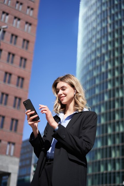 Retrato de empresária de sucesso tendo uma conversa telefônica em fones de ouvido sem fio andando