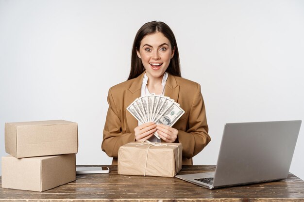 Retrato de empresária sentada no escritório com dinheiro trabalhando e obtendo lucro posando feliz...