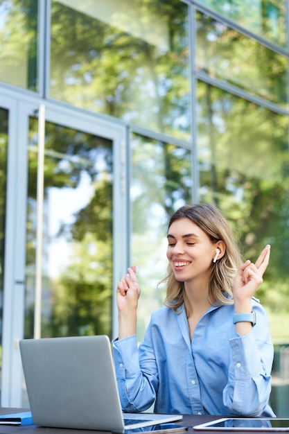 Foto grátis retrato de empresária sorridente e animada sentada com laptop faz gestos de dedos cruzados