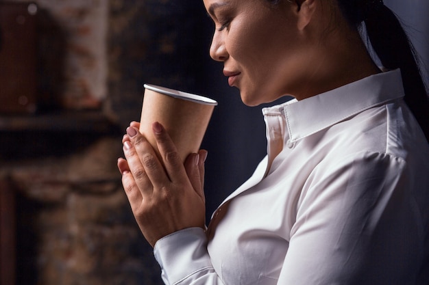 Retrato de empresária tomando café isolado em fundo escuro