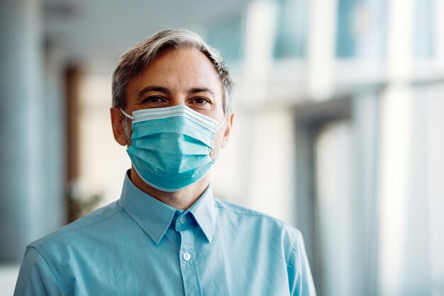 Retrato de empresário adulto médio com máscara facial protetora no escritório