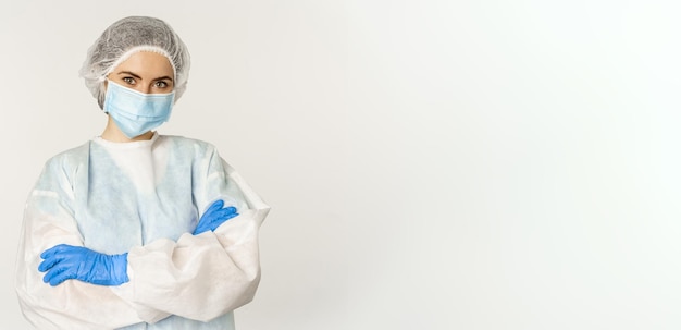 Retrato de enfermeira médica em equipamento de proteção individual parecendo confiante e profissional em pé sobre fundo branco