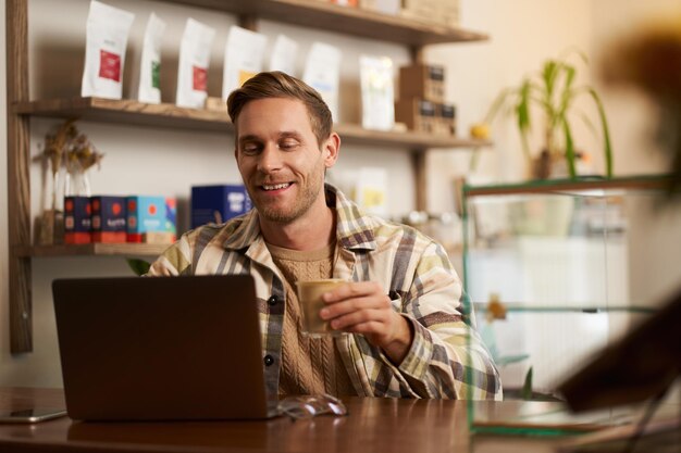 Retrato de estilo de vida de um jovem empresário freelancer sentado em um café bebendo café e usando um laptop