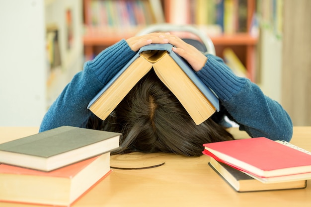 Retrato de estudante inteligente com livro aberto, lendo na biblioteca da faculdade