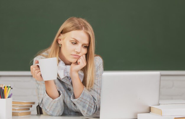 Retrato de estudante universitária estuda lição bebendo café ou chá na escola ou universidade