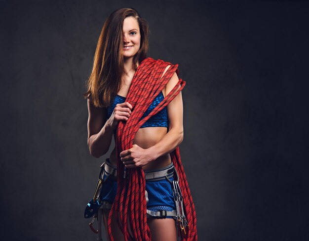 Retrato de estúdio de alpinista livre feminino detém, corda de escalada sobre fundo cinza.