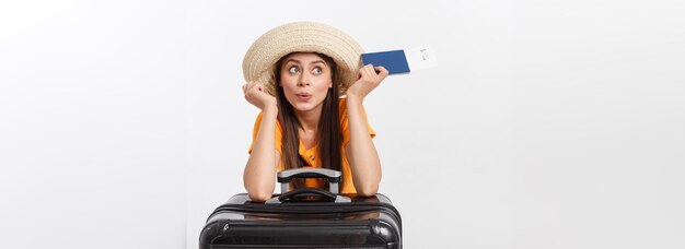 Retrato de estúdio de conceito de viagem de uma jovem bonita segurando passaporte e bagagem isolada em branco