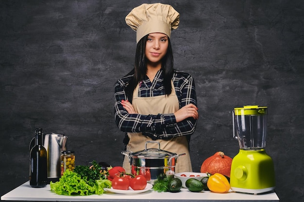 Retrato de estúdio de cozinheiro feminino chef à mesa com um monte de legumes.