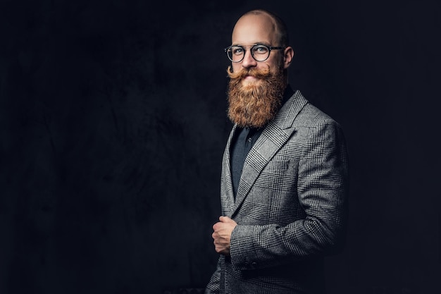 Retrato de estúdio de homem barbudo ruivo em óculos vintage, vestido com uma jaqueta de lã.