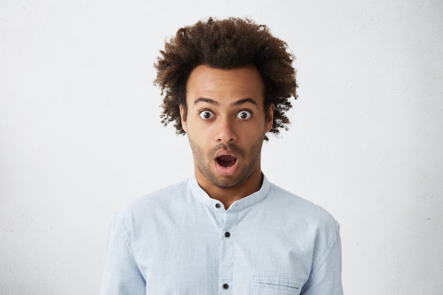 Retrato de estúdio de um homem de pele escura com olhos esbugalhados e cabelo escuro e espesso e eriçado e surpreso