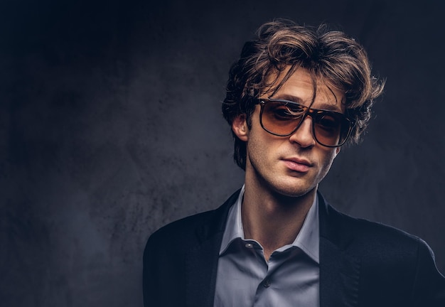 Retrato de estúdio de um macho sensual carismático com cabelo elegante e óculos de sol