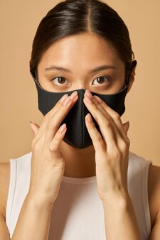 Retrato de estúdio de uma jovem vestindo uma máscara facial preta, olhando para a câmera enquanto posa