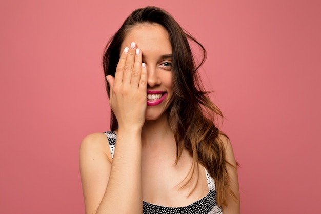 Foto grátis retrato de estúdio de uma mulher europeia atraente sorridente posando sobre uma parede rosa isolada