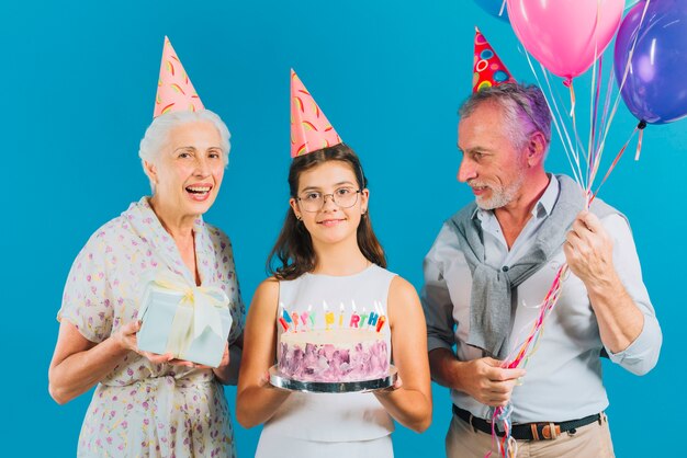 Retrato de família com bolo de aniversário; presente e balões em fundo azul