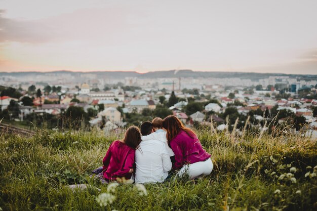 Retrato de família. Homem, duas mulheres e um menino sentam na grama