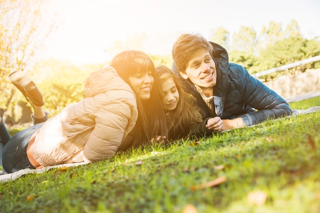 Foto grátis retrato, de, feliz, família, deitando-se, capim, parque