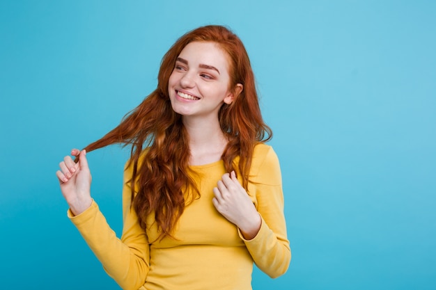 Retrato de feliz gengibre menina de cabelo vermelho com sardas sorrindo olhando câmera. Fundo azul Pastel. Espaço de cópia.