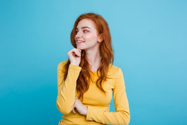 Retrato de feliz gengibre menina de cabelo vermelho com sardas sorrindo olhando câmera. Fundo azul Pastel. Espaço de cópia.