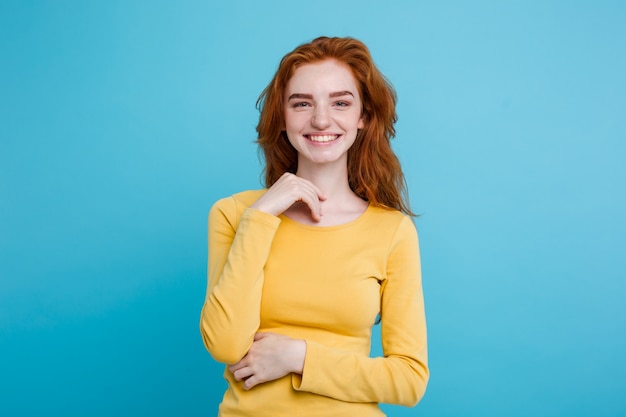 Retrato de feliz gengibre menina de cabelo vermelho com sardas sorrindo olhando câmera. Fundo azul Pastel. Espaço de cópia.