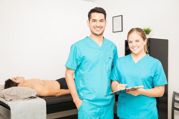 Retrato de fisioterapeutas masculinos e femininos com prancheta em pé no hospital