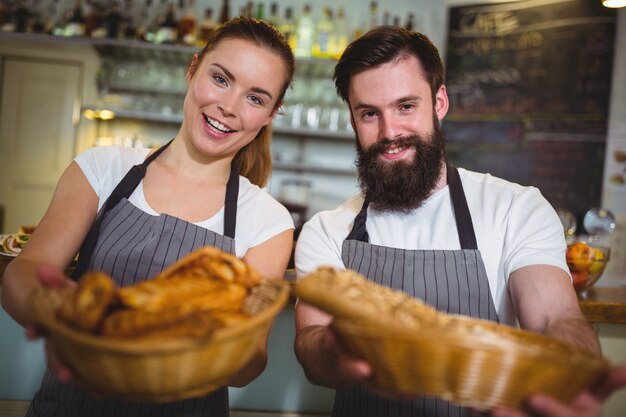 Retrato de garçom e garçonete segurando uma cesta de pão