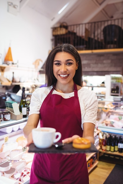 Retrato de garçonete segurando uma xícara de café e lanches