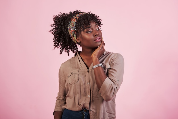 Retrato de garota afro-americana atraente em roupas casuais e relógio na mão posando para a câmera