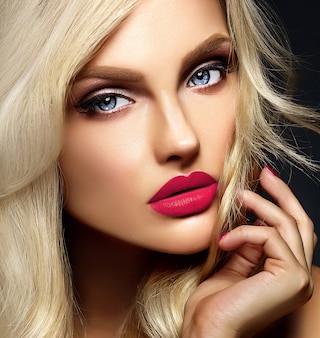 Retrato de glamour sensual da senhora modelo linda mulher loira com maquiagem brilhante e lábios cor de rosa, com cabelos cacheados saudáveis em fundo preto