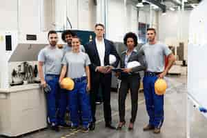 Foto grátis retrato de grupo de engenheiros e gerentes corporativos em uma fábrica e olhando para a câmera