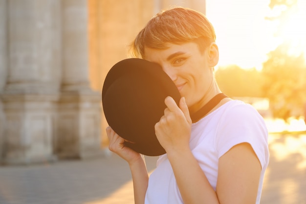 Retrato de hipster feminino com maquiagem natural e cabelo curto, aproveitando o tempo de lazer ao ar livre