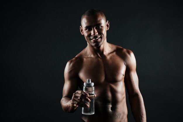 Retrato de homem afro-americano jovem esportes sorridente, segurando a garrafa de água