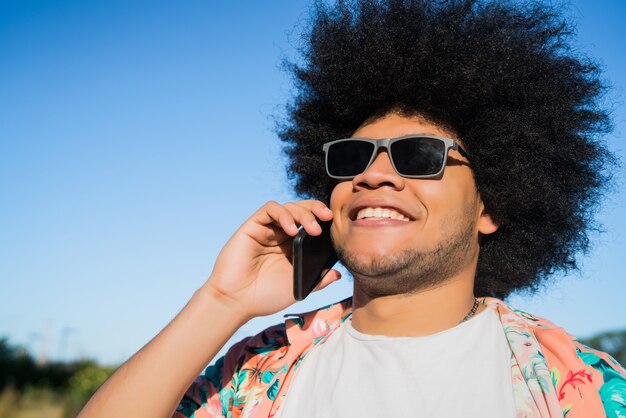 Retrato de homem afro-latino falando ao telefone em pé ao ar livre na rua