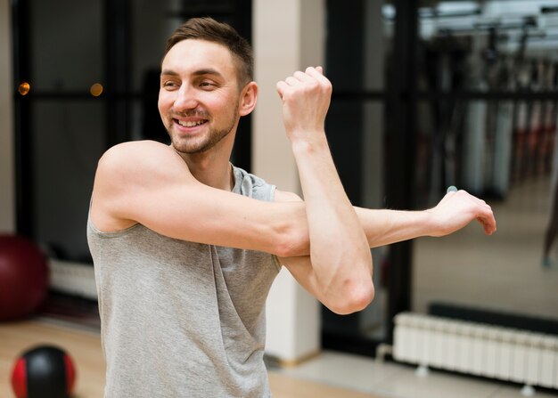 Foto grátis retrato de homem apto, estendendo-se na academia