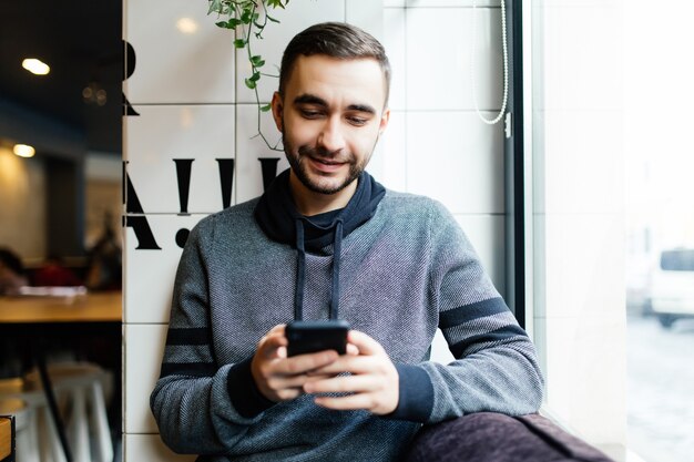 Retrato de homem barbudo com telefone celular em um café