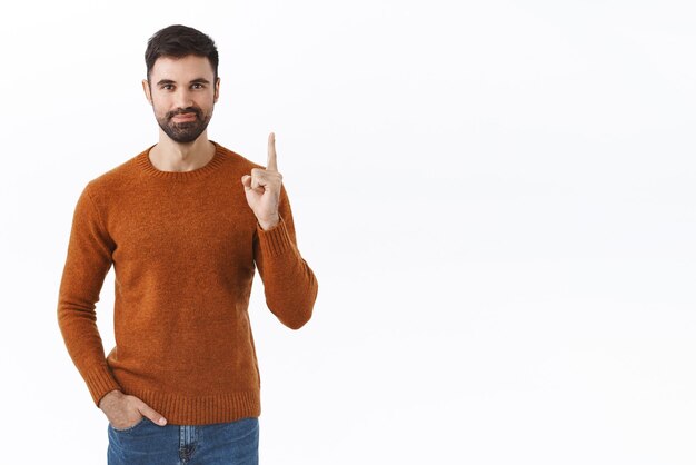 Retrato de homem barbudo inteligente confiante apontando o dedo para cima mostrando caminho para o anúncio sorrindo convidando para o conteúdo de checkout dar recomendação o que escolher fundo branco