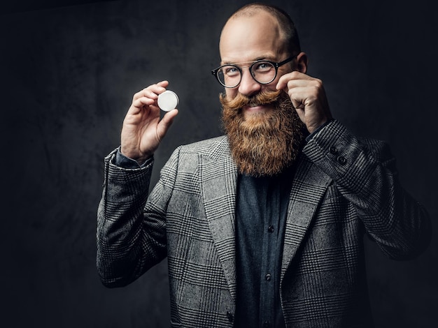 Retrato de homem barbudo ruiva em óculos vestido com um terno de lã elegante sobre fundo cinza.