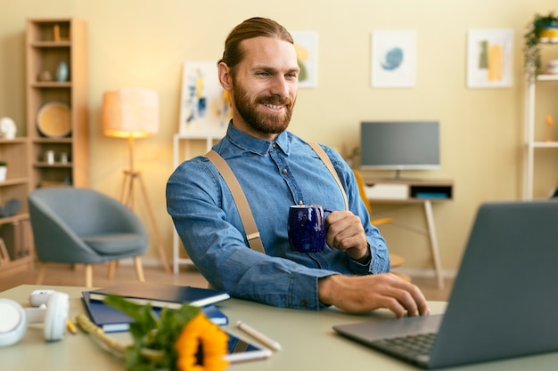 Foto grátis retrato de homem barbudo trabalhando no laptop