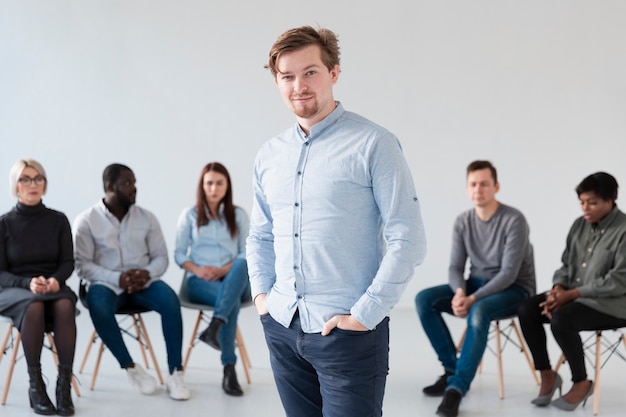 Retrato de homem bonito com pacientes de reabilitação por trás