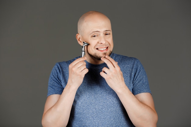 Retrato de homem bonito engraçado na camisa cinza de barbear parede escura